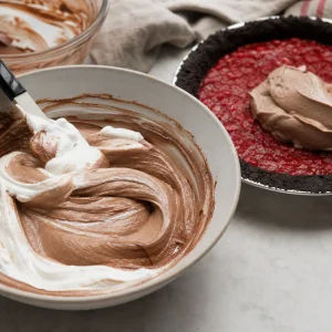 Whipped cream folded into chocolate custard beside the pie