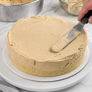 Sorvete de caramelo amolecido espalhado uniformemente sobre a camada de bolo fria