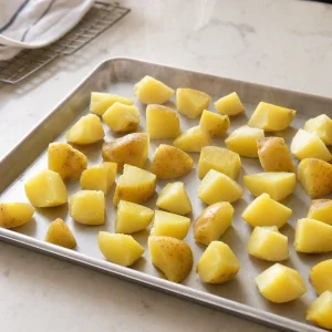 Drained potato chunks steam-drying on a sheet pan