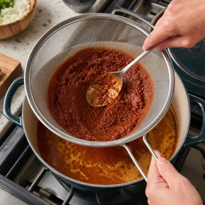 Red chile sauce strained through a fine-mesh sieve into the broth