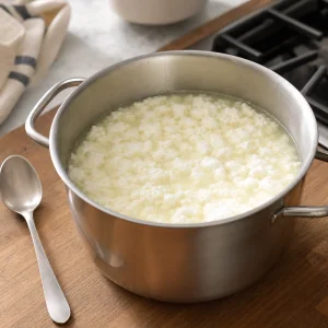 Separated curds and pale whey resting undisturbed in the pot