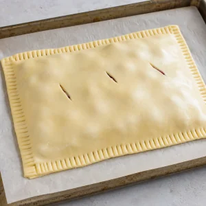 Sealed puff pastry cherry cake with small steam slits cut on top
