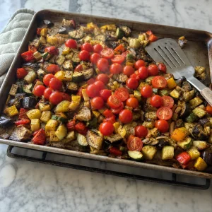 Légumes partiellement rôtis mélangés avec des tomates cerises fraîches sur la plaque chaude.