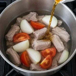 Gereinigte Schweinerippchen mit Zwiebel und Tomaten, während Fischsauce zugegeben wird
