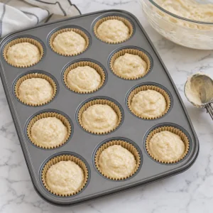 Keto muffin batter portioned into parchment lined muffin cups two thirds full
