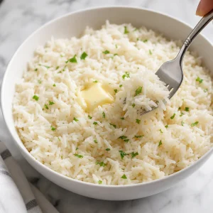 Fluffy white rice being lifted with a fork and melting butter