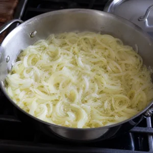 Thinly sliced onions softening in butter and olive oil