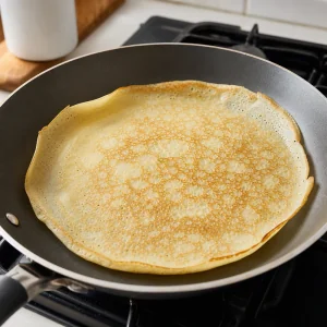 Crepe cooking until lightly browned with edges lifting