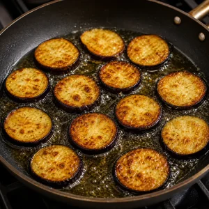 Fette di melanzana che friggono nell’olio bollente fino a dorarsi