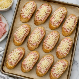 Geriebener Kaese auf Knoblauchtoasts mit Schinken