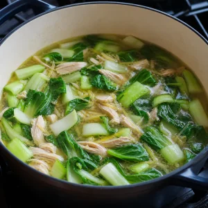 Baby bok choy simmering with shredded chicken in ginger broth