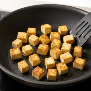Tofu cubes browning in a nonstick skillet