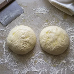 Focaccia dough divided into two pieces on a floured surface