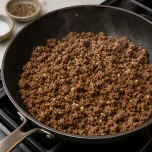 Bœuf haché doré qui cuit avec de l’ail dans une poêle.