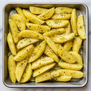 Potato wedges coated with olive oil, oregano, lemon zest, salt, and pepper