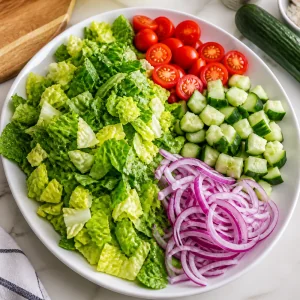 Chopped romaine, tomatoes, cucumber, and red onion on a platter