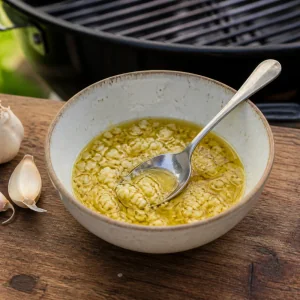 Aglio tritato mescolato con olio d'oliva accanto alla griglia