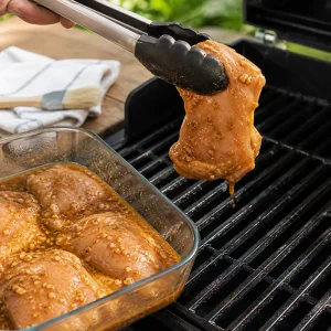 Frango marinado escorrendo ao lado da grelha quente untada