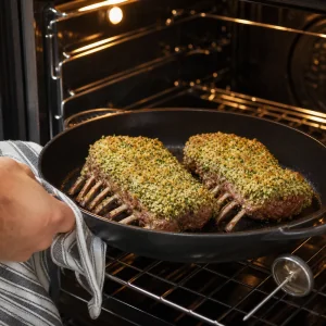 Herb-crusted lamb racks roasting bone-side down in the oven