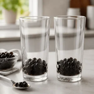 Perle di tapioca cotte divise in modo uniforme tra due bicchieri alti trasparenti