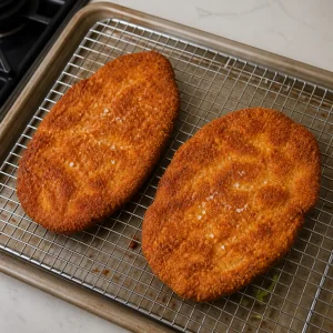 Freshly fried schnitzel resting on a wire rack