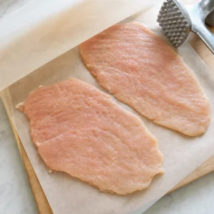Thin chicken cutlets flattened on parchment