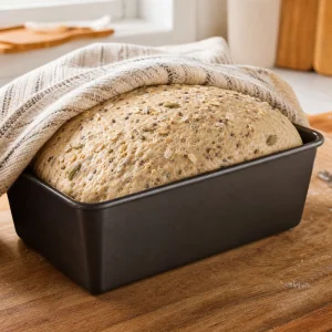 Proofed seeded loaf risen above the rim of the loaf pan