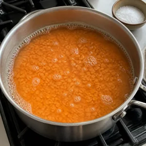 Rote Linsen und Wasser kochen in einem Topf auf