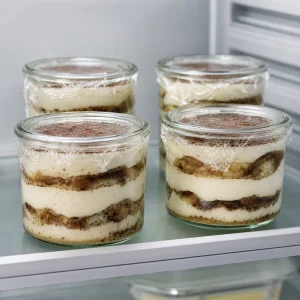 Vasetti di tiramisù coperti che si rassodano su un ripiano del frigorifero
