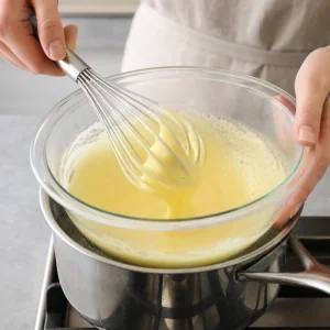 Tuorli e zucchero montati a bagnomaria fino a ottenere uno zabaione chiaro