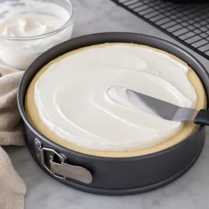 Cobertura de sour cream espalhada de forma lisa sobre o cheesecake.