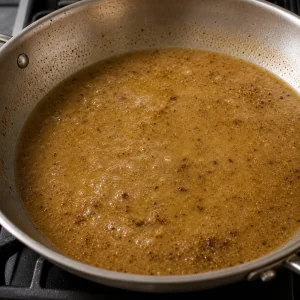 Light golden pan sauce simmering after chicken broth is added