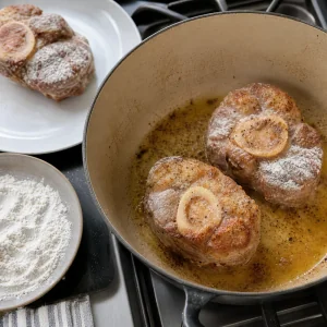 Floured veal shanks browning in a Dutch oven
