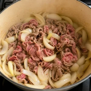 Dünne Rindfleischscheiben garen mit Zwiebeln im Topf
