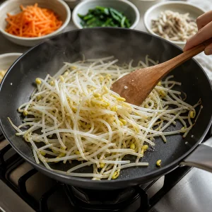 소고기 비빔밥용 숙주를 뜨거운 팬에서 짧게 볶는 모습.