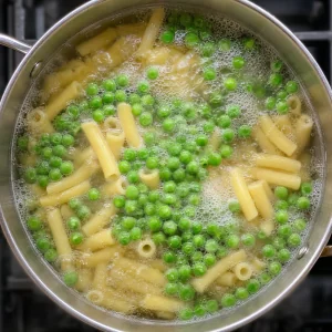 Bright green peas cooking with short pasta