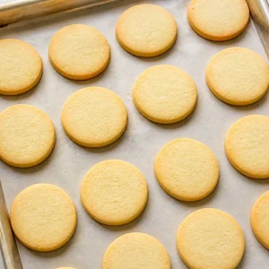 Baked shortbread rounds with lightly golden edges on a sheet pan