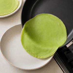 Crepe verde de pandan cocida pasando de la sartén a un plato