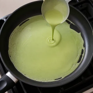 Masa verde de pandan extendiéndose en una sartén