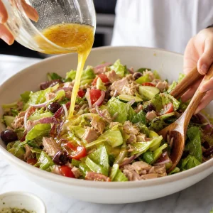 Lemon dressing poured over Mediterranean tuna salad while gently tossing