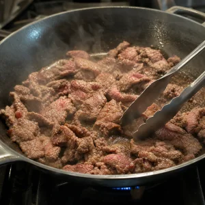 Steak strips searing quickly in a hot skillet