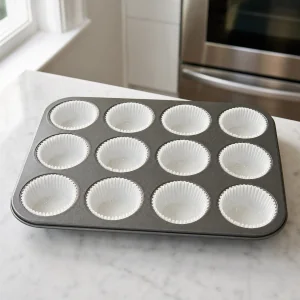 Muffin pan prepared with twelve paper liners