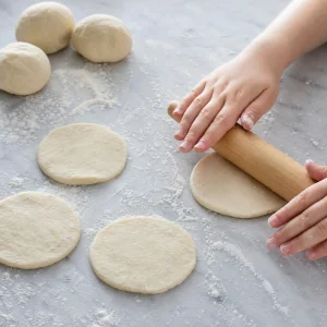 Small pizza dough rounds rolled flat on a floured surface