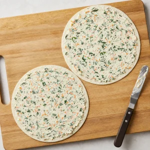 Fromage frais aux légumes cachés étalé uniformément jusqu'aux bords des tortillas