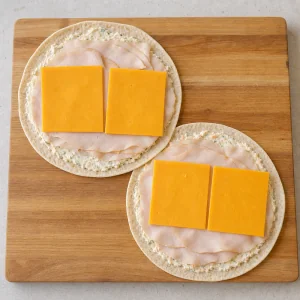 Tranches de dinde et cheddar disposés sur des tortillas au fromage frais aux légumes
