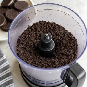 Biscuits sandwich au chocolat reduits en fines miettes dans un robot culinaire