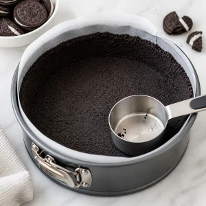 Base oscura de migas de Oreo presionada en el molde
