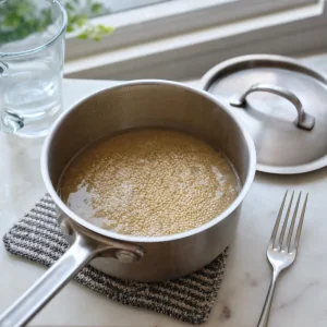 Quinoa simmering in a small saucepan until the water is absorbed