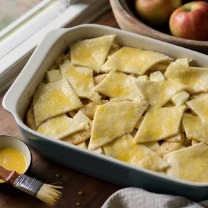 Unbaked apples covered with egg-washed pastry pieces