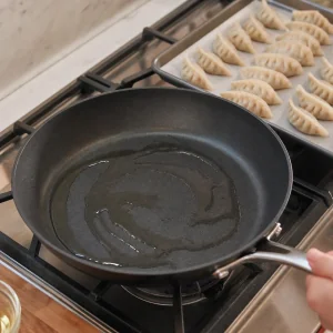뜨거운 팬에 식물성 기름을 두르고 옆 쟁반에 주름 잡은 생 자오쯔를 준비한 모습